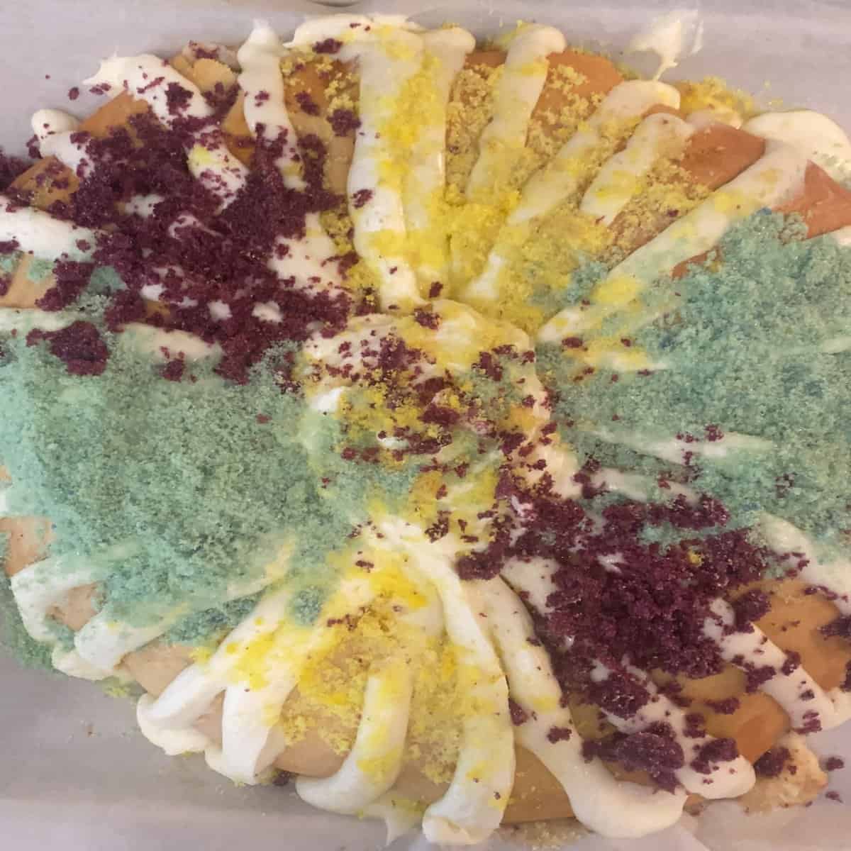 sourdough king cake with yellow, green, purple icing sugar